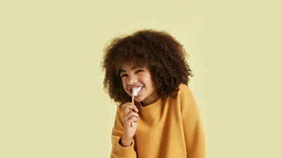 Cute kid brushing teeth with Schmidt's Kids Toothpaste in Coconut+Pineapple